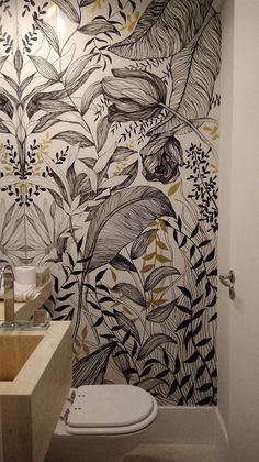 a bathroom with a toilet, sink and wallpaper in black and white colors on the walls