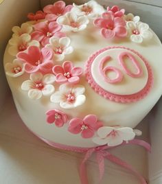 a white cake with pink and white flowers in the shape of a number sixty on it