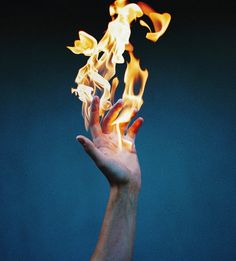 a hand with flames coming out of it's palm is shown in front of a blue background