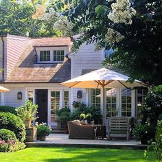 an outside view of a house with lawn chairs and umbrellas