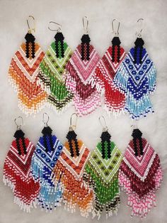 six pairs of beaded earrings in different colors and designs on a white surface with black beads