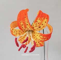 an orange crocheted flower in a glass vase