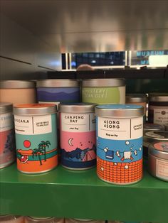 several tins of food sitting on top of a green shelf