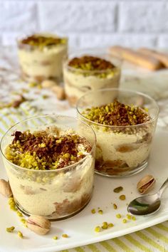 three desserts with nuts and pistachio in small glass dishes on a white tray