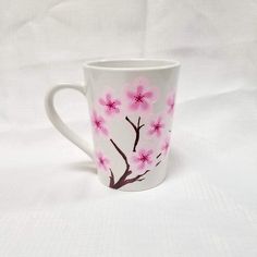 a white coffee cup with pink flowers painted on the outside and inside, sitting on a white surface