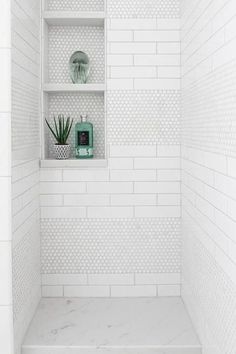 a white tiled shower with shelves and plants