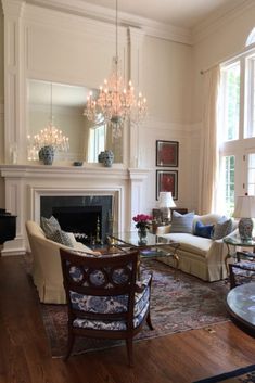 a living room filled with furniture and a chandelier hanging from the ceiling next to a fire place