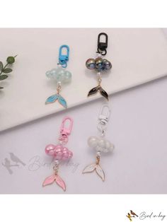 four different colored charms on a white surface