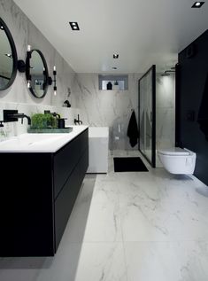 a modern bathroom with black and white walls, marble flooring and large mirror on the wall