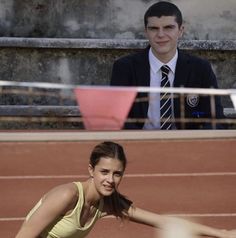 a woman is playing tennis on the court with a man in the back ground behind her