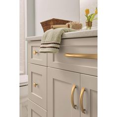 a bathroom with white cabinets and gold handles