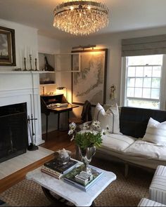 a living room filled with furniture and a chandelier hanging from the ceiling over a fire place