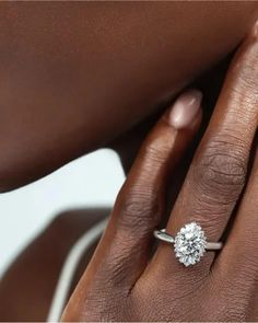 a woman's hand with a diamond ring on her left hand and the other hand holding an engagement ring