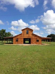 a large wooden barn sitting on top of a lush green field