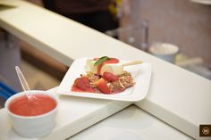 a white plate topped with food next to a bowl of fruit and sauce on top of a counter