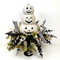 three pumpkins are stacked on top of each other with black and white ribbons around them