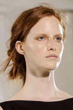 a woman with freckles on her face is staring at the camera while wearing a black dress