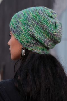 a woman wearing a green and white knitted beanie with ear rings on her head