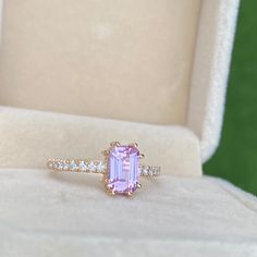 an engagement ring with a pink sapphire surrounded by diamonds in a white velvet gift box