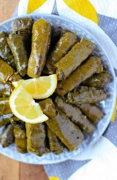 a plate full of stuffed grape leaves and lemon wedges