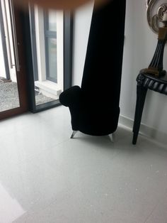 a black chair sitting on top of a white floor next to a door and window