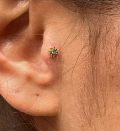 a woman's ear with a small green stone in the middle