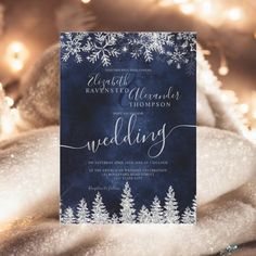 a blue and white wedding card with snowflakes on it, surrounded by christmas lights