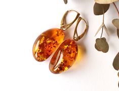 The earrings of Baltic amber in rich honey colour will not betray your expectations. It is one of the most popular colours of Baltic amber.  These elegant, sophistically sparkling earrings with a spangle inside are an irresistible piece of jewellery that you will love wearing every day. It is a genuine, natural and unique piece of jewellery created by nature, so you will feel special on every occasion. Delight yourself or your loved one with a little miracle from nature.  Earrings length with clasp: 5 cm. / 1.96 inch Weight: 9.6 g / 0,33 oz Color: cognac, golden Natural Baltic amber 925 sterling silver gold plated The world is continuously moving forward, evolving and changing at a rapid pace. Baltic amber jewellery has 30 million years of history behind and is a lovely bridge between the Cheap Amber Dangle Jewelry, Formal Baltic Amber Earrings, Gem Stone Earrings, Baltic Amber Jewelry, Clear Earrings, Golden Amber, Golden Earrings, Amber Earrings, Amber Bracelet