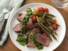 a white plate topped with meat and veggies next to a glass of water