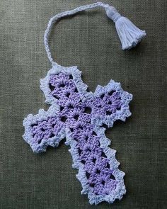 a crocheted purple cross with tassels is laying on a tablecloth