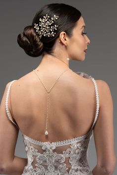 the back of a woman wearing a wedding dress with pearls and beads on her neck