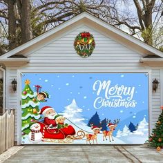 a garage decorated for christmas with santa clause and reindeers on the front door, surrounded by trees