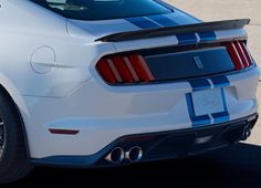 the rear end of a white mustang with blue stripes