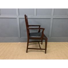 a wooden chair with black leather seat and armrests in front of a wall