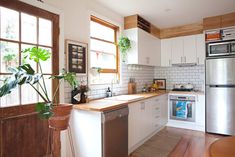 a kitchen with white cabinets and stainless steel appliances in it's center island next to a potted plant