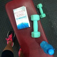 a person standing next to a skateboard with a book and dumbs on it