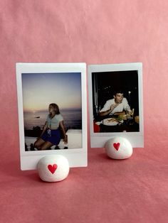 two polaroid frames sitting next to each other on a pink surface with hearts in the middle