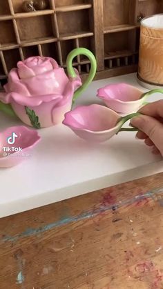 a person is making pink flowers out of clay