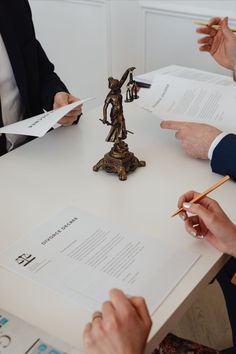 three people sitting at a table with papers in front of them and one person holding a pencil