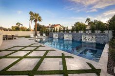 an outdoor swimming pool with artificial grass in the foreground and palm trees on the other side