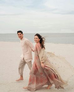 a man and woman are walking on the beach