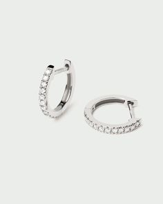 two silver hoop earrings with small white stones on the inside and outside of each ear