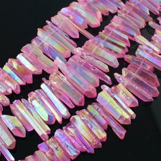 many pink and white beads are lined up on a black surface with one bead in the middle