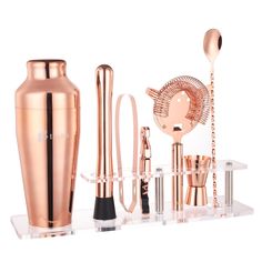 an assortment of rose gold colored items including a cocktail shaker, spoons and cups