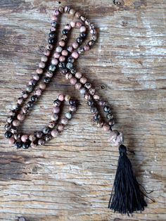 "MALA (108 bead count plus guru bead) Rhodonite Natural Gemstones Larger \"Guru\" bead is Saturn shaped Knotted between the beads on silk thread. Beads are approx. 8mm Guru Bead approx. 18x20mm Overall length approx. 38\" (not including the guru bead) Drop length with tassel is 2.75\" Tassel is black in color. All measurements are approximate. All jewelry will be shipped in a gift box or pouch at my discretion. Please check out my other listings for more jewelry :)" Spiritual Hand Knotted Beaded Necklaces For Festivals, Spiritual Hand Knotted Beaded Necklace For Festivals, Hand-knotted Beaded Necklaces For Meditation, Hand Knotted Beaded Necklaces For Meditation, Bohemian Hand Knotted Beads As Gift, Bohemian Hand-knotted Beads For Gift, Spiritual Hand-knotted Beaded Necklaces With Round Beads, Spiritual Hand-knotted Beaded Necklaces, Artisan Hand-knotted Beaded Necklaces For Meditation