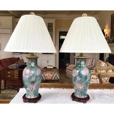 two lamps sitting on top of a table in front of a living room couches