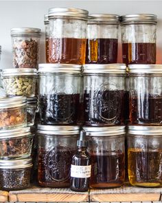 many jars filled with different types of food on a wooden shelf next to each other