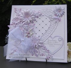 a white card with purple flowers on it and a ribbon tied around the front of it