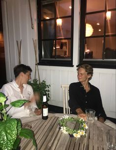 two people sitting at a table with wine and flowers