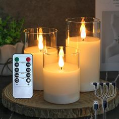 three lit candles with remote controls sitting on a table